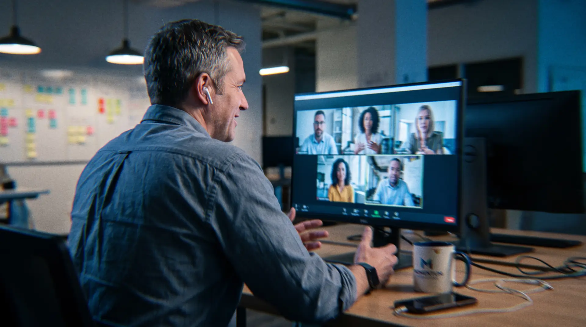 Executive managing an offshore marketing team on a video call, illustrating remote international hiring and offshore staffing costs in a dimly lit office.