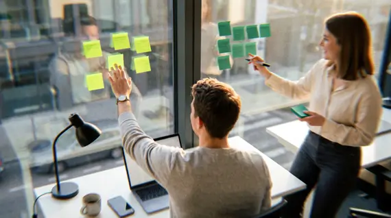 Founder and operations manager sorting sticky notes on an office window to decide which roles can be outsourced to remote international employees, by function