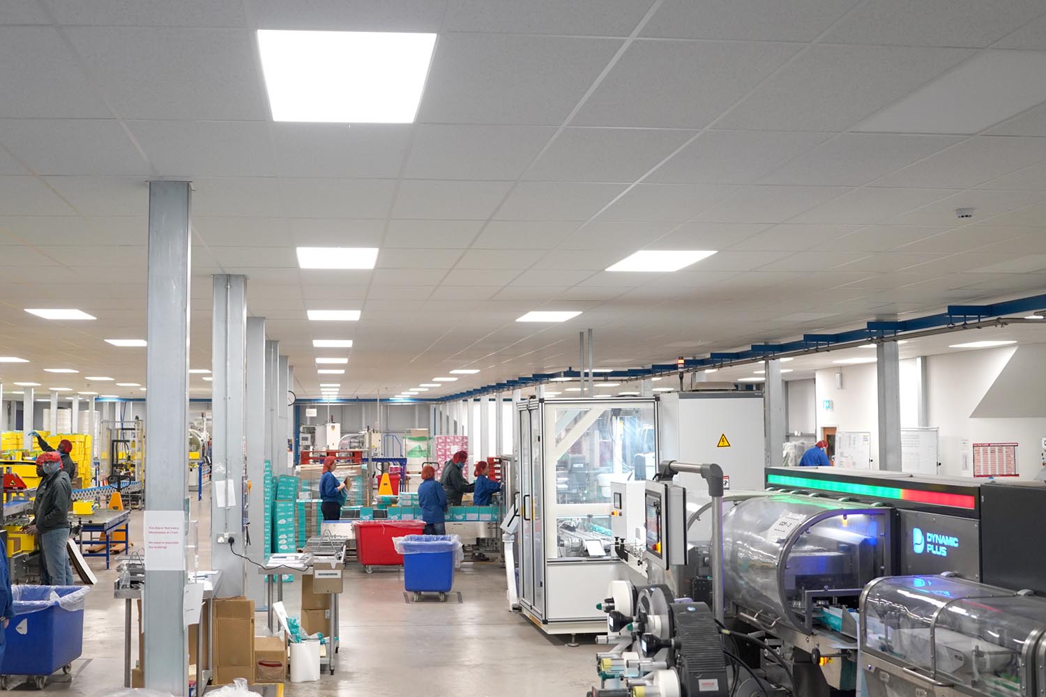 Large, clean factory floor with workers wearing hair nets and machinery for packaging products.