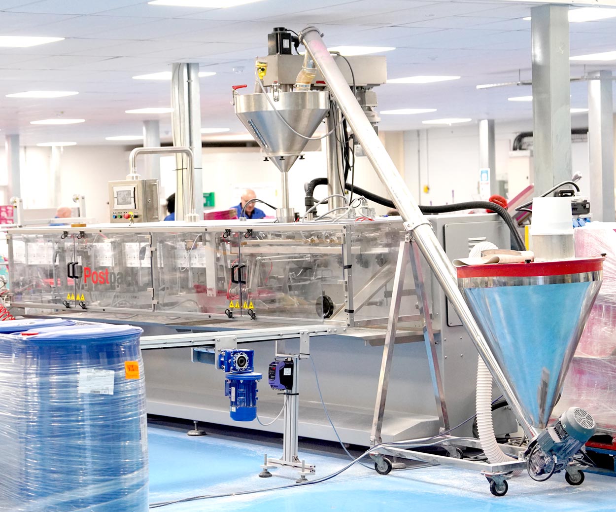 Industrial powder production equipment with metal funnel, conveyors, and machinery in a factory setting.