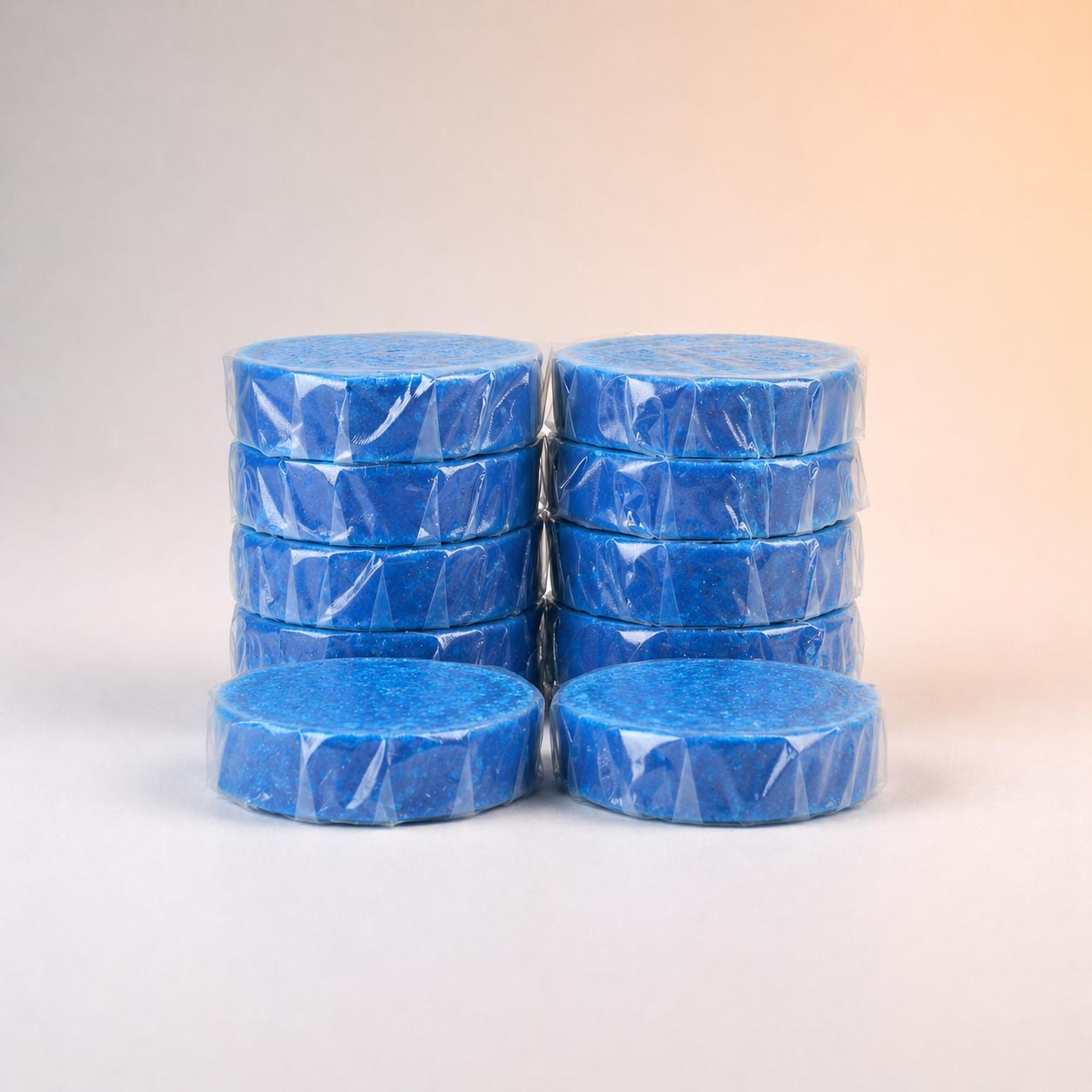 Stacks of blue round toilet cleaner blocks individually wrapped in clear plastic.