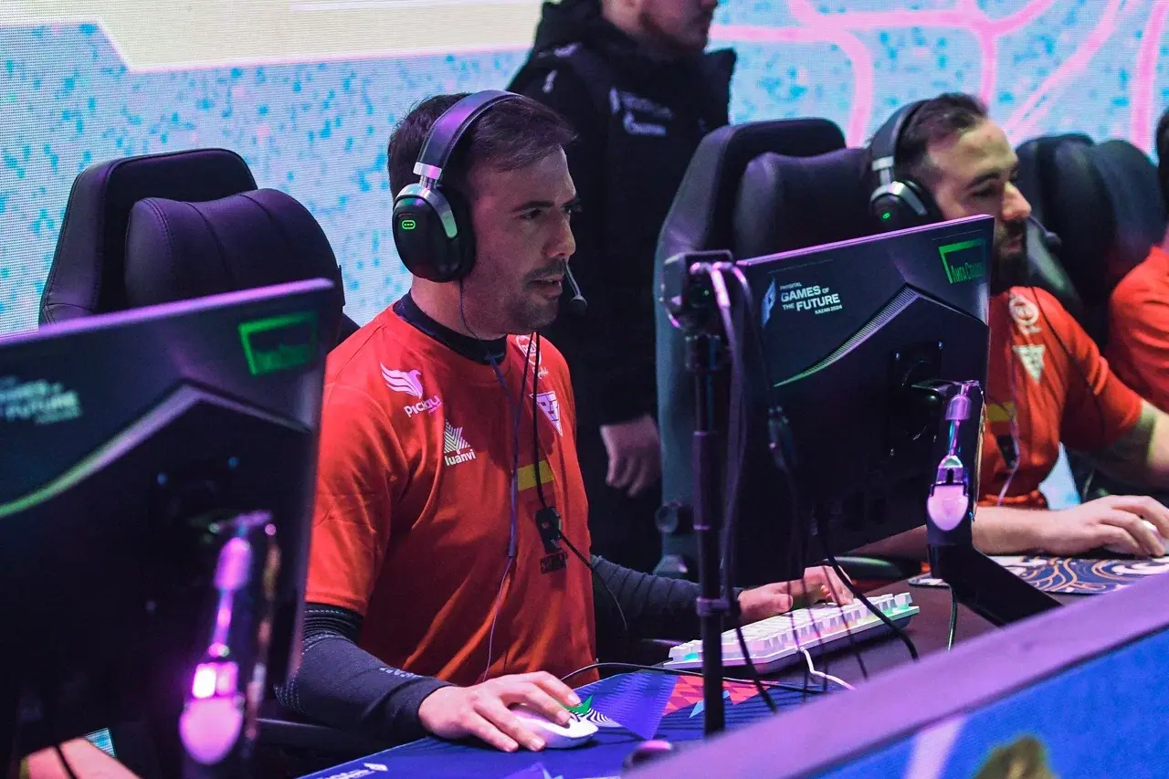 Audience watching a competitive esports match on large screens with highlighted player stats and team names Monster Gaming and Entity in a lit arena.