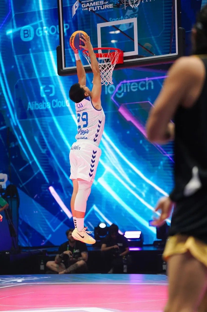 Basketball player in red jersey jumping for a layup while a defender in black jersey tries to block.