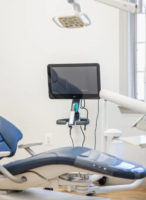 Modern dental chair with a mounted screen and attached intraoral scanner in a bright dental office.