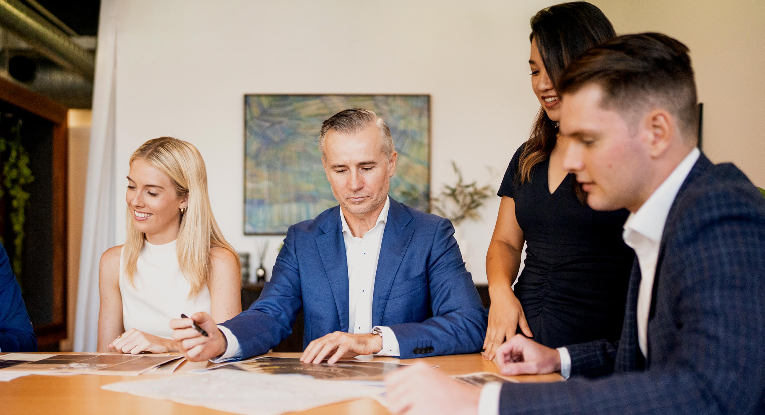 Realm Projects team discussing documents around a table in a modern office setting.