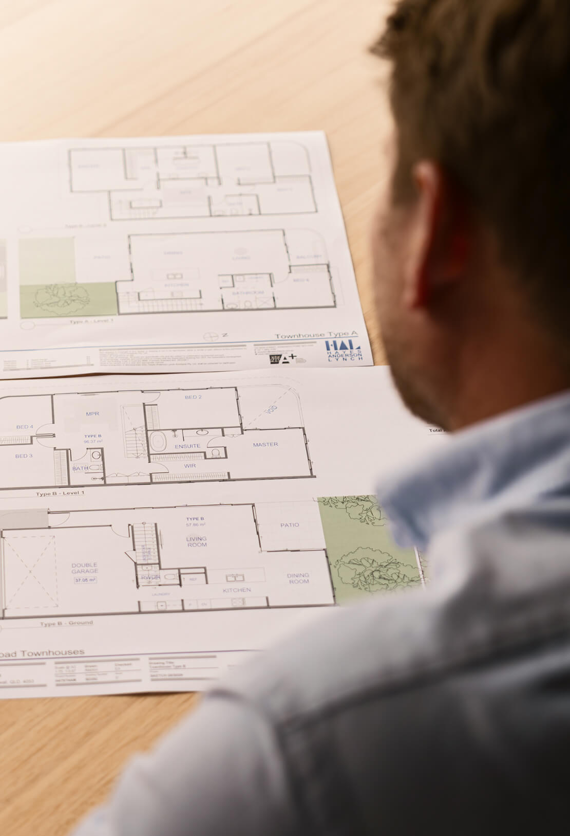 A person in a suit is reviewing a detailed architectural design print of a building's exterior, highlighting features with a pen.