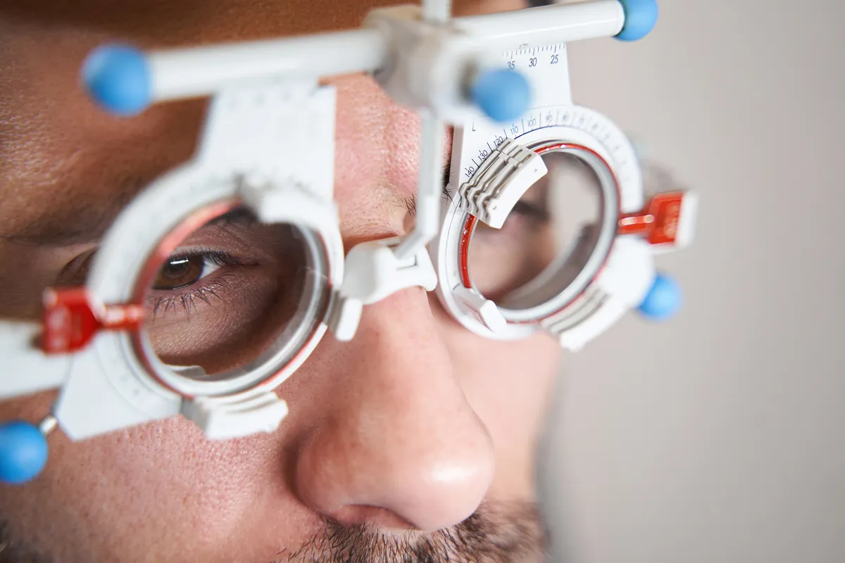 Close-up of a man with brown eyes wearing a white trial frame used for eye exams.
