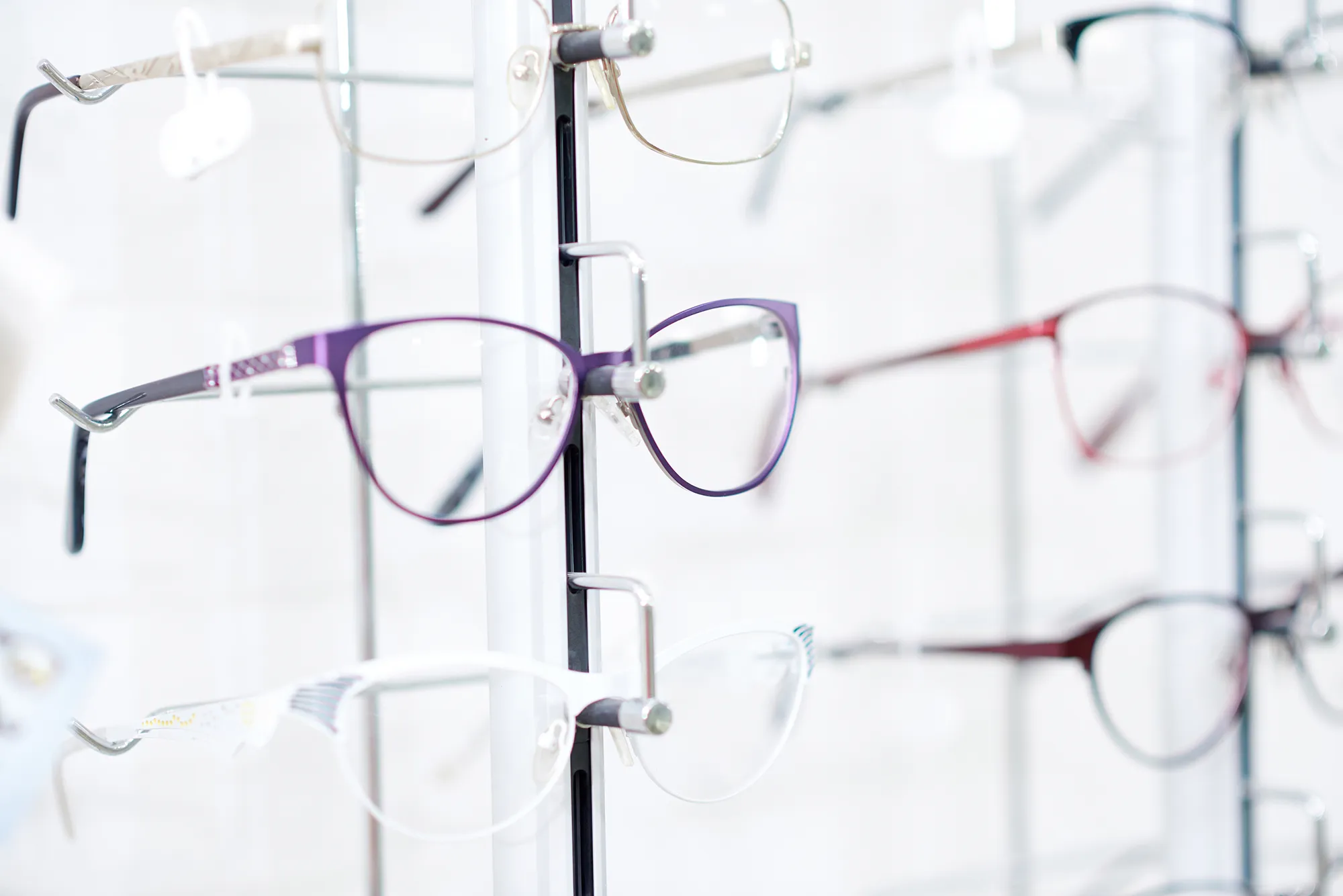 Various eyeglass frames displayed on a vertical stand in an optical store.