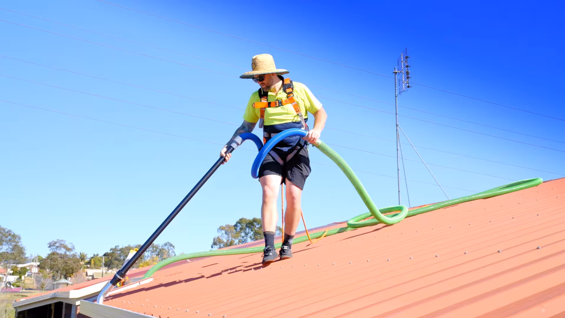 Technician performing gutter cleaning and vacuuming on rooftop