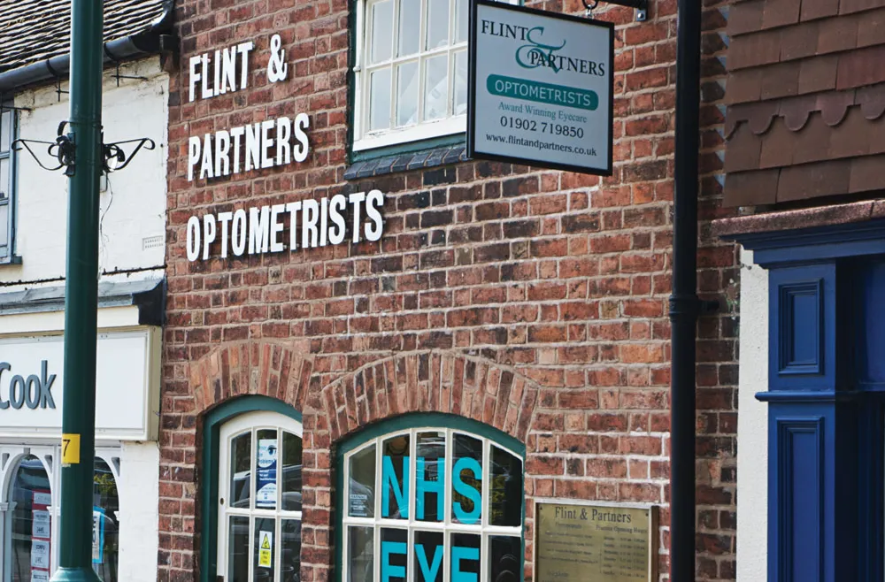 Brick building with Flint & Partners Optometrists signage and NHS Eye displays in windows.