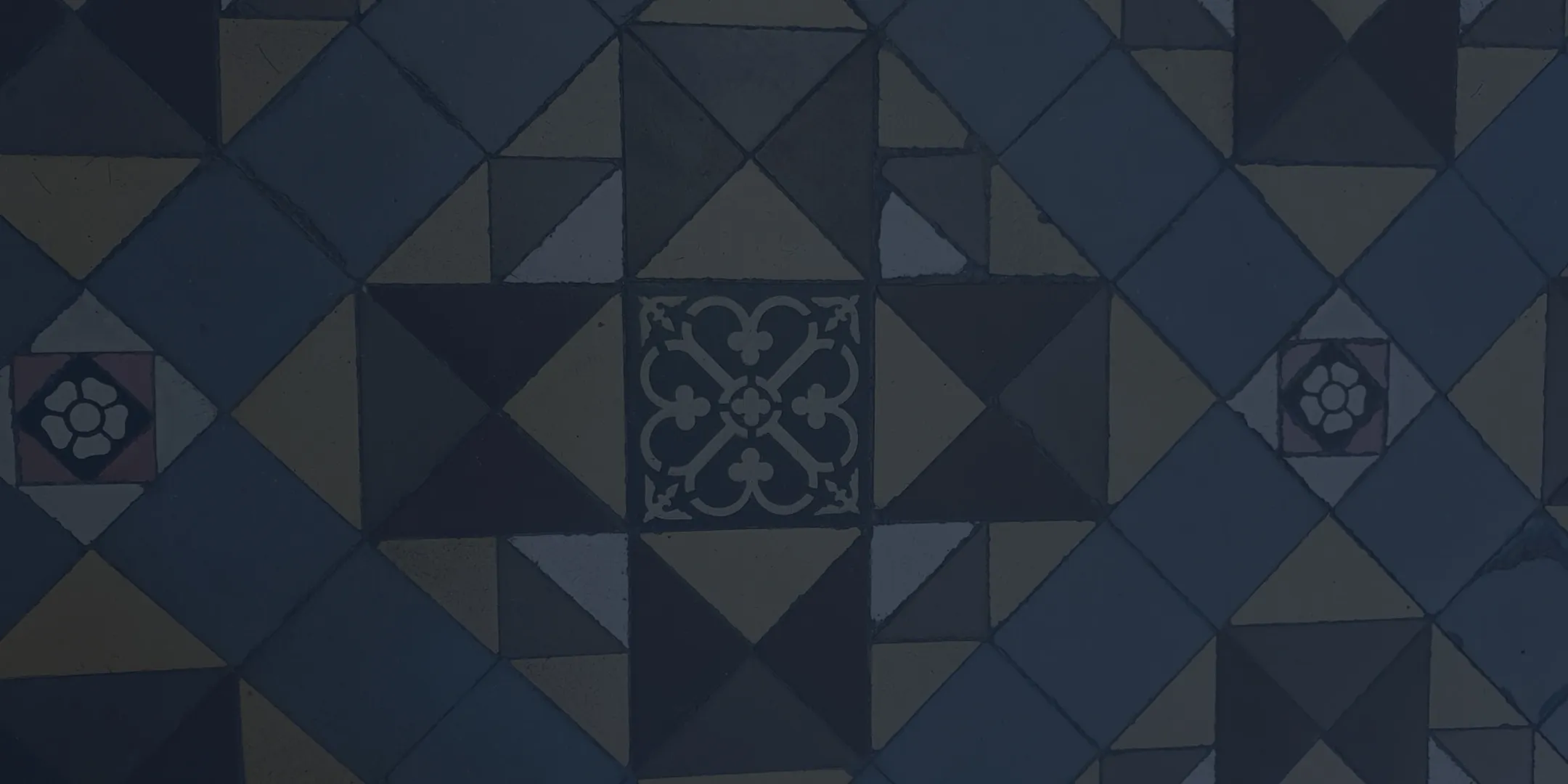 Geometric patterned floor tiles with squares, triangles, and floral motifs in muted colors.
