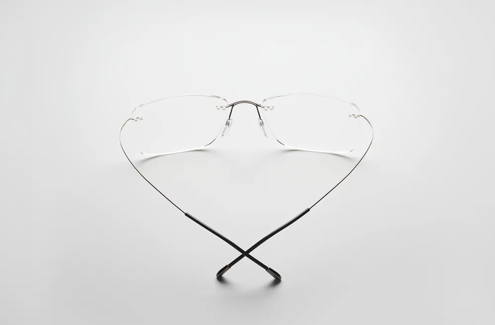 Thin-rimmed eyeglasses with temples crossed, placed on a gray background.