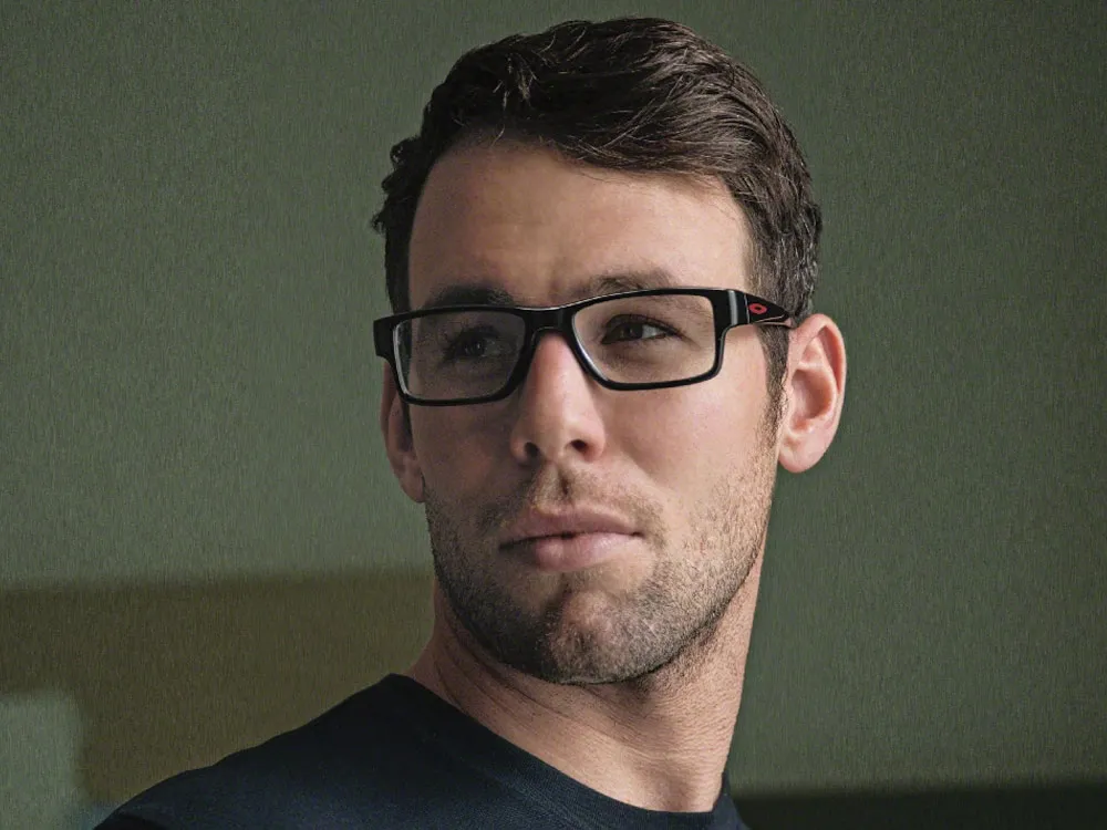 Man wearing rectangular black Oakley glasses frames against a green background.