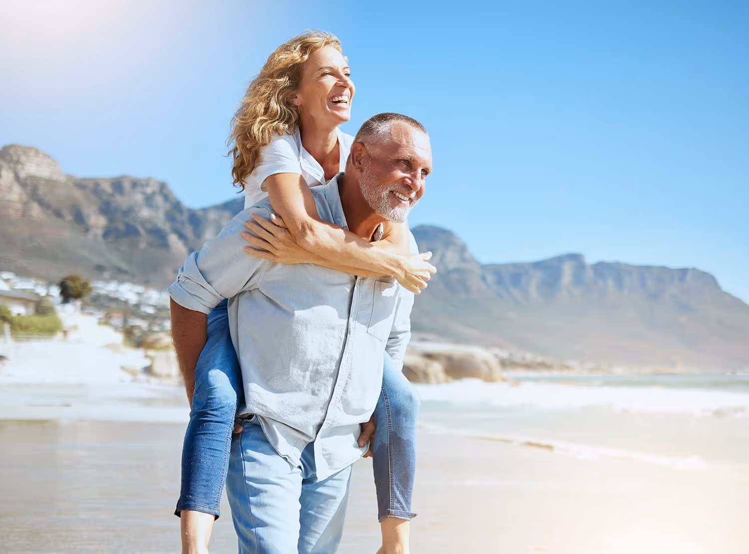 Senior couple on the beach smiling and playing, enjoying life with better hearing and connection