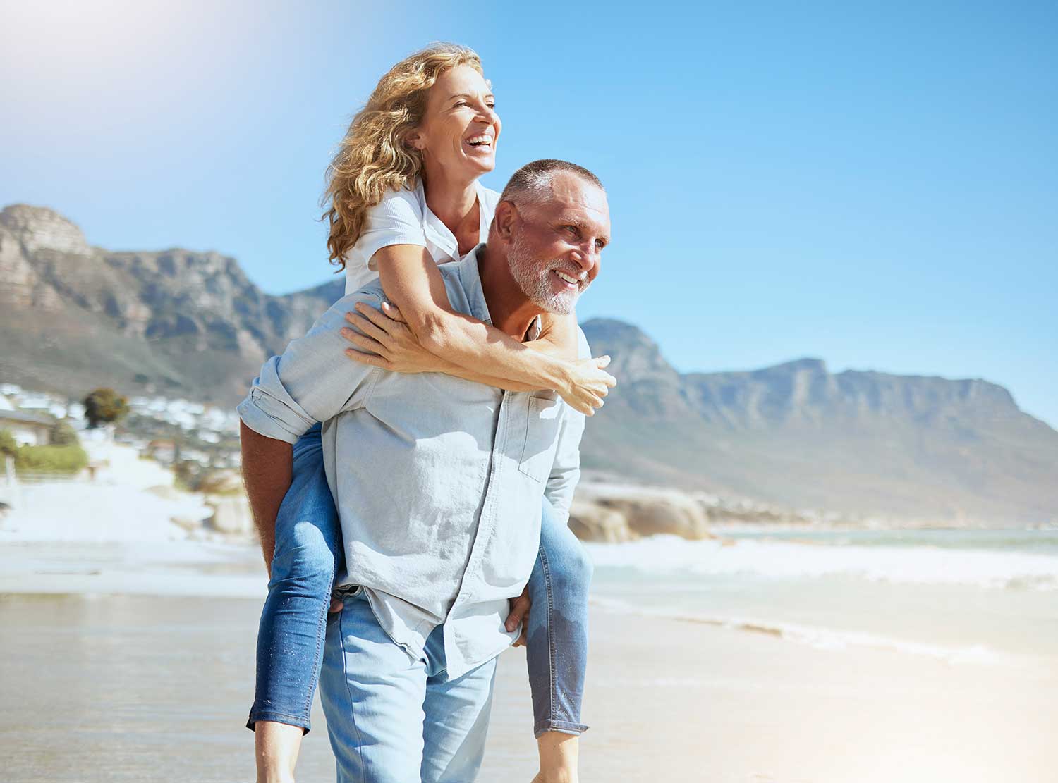 Senior couple on the beach smiling and playing, enjoying life with better hearing and connection