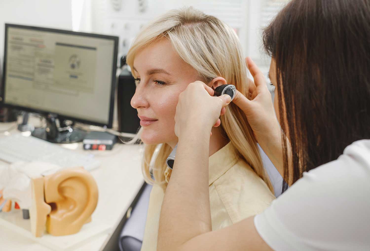 Audiologist performing a hearing test by examining a patientβs ear in a clinical setting