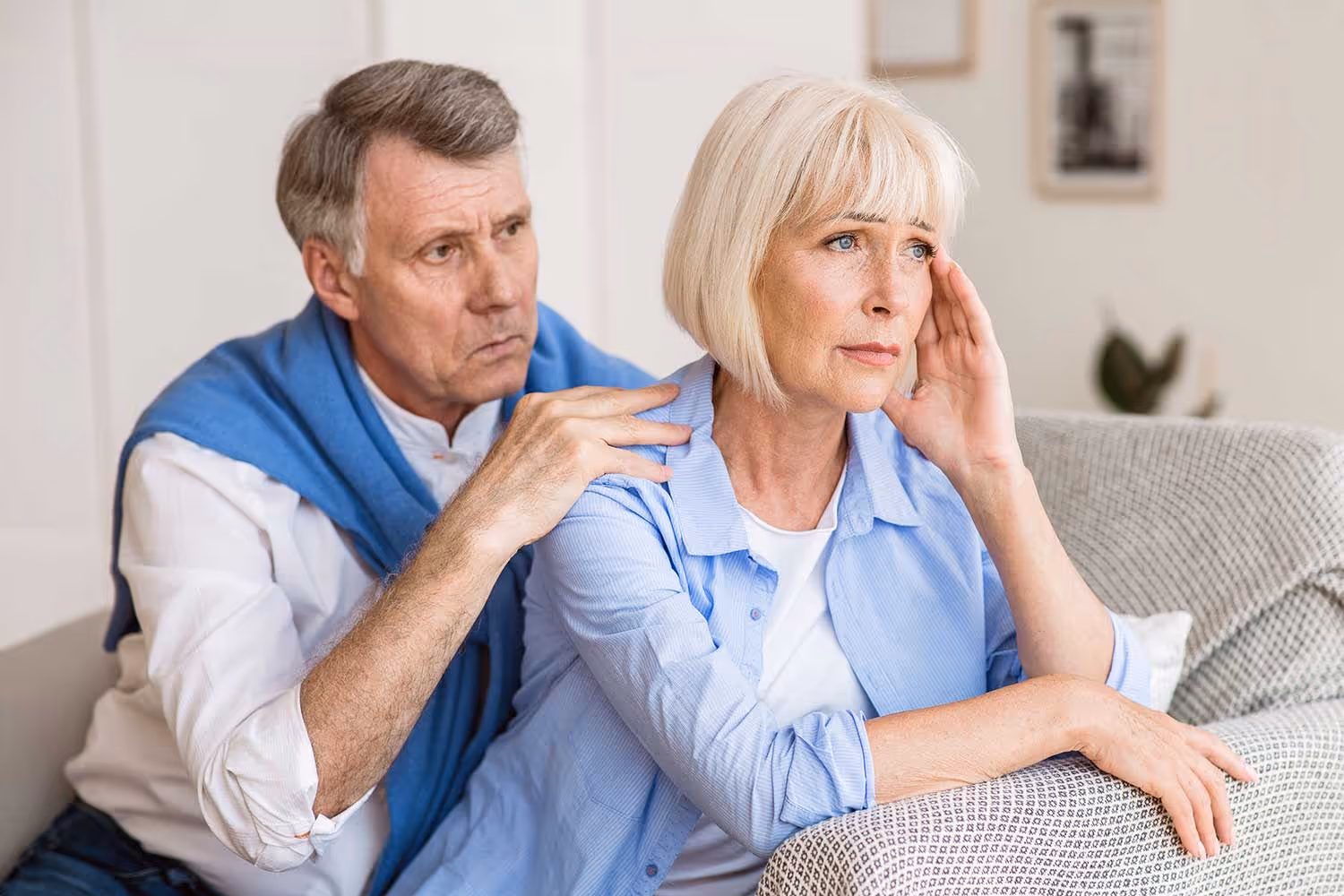 Older couple experiencing difficulty hearing during a conversation, showing signs of hearing loss and frustration.