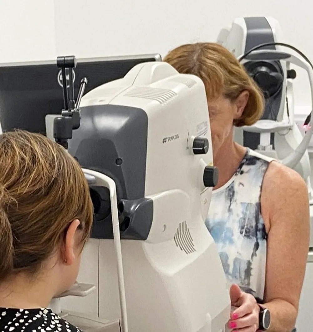 Eye exam being conducted using a Topcon eye scanning machine in a clinical setting.