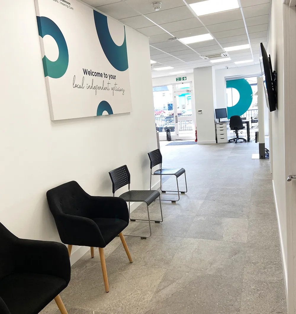 Modern waiting area with black chairs and a welcome sign for local independent opticians.