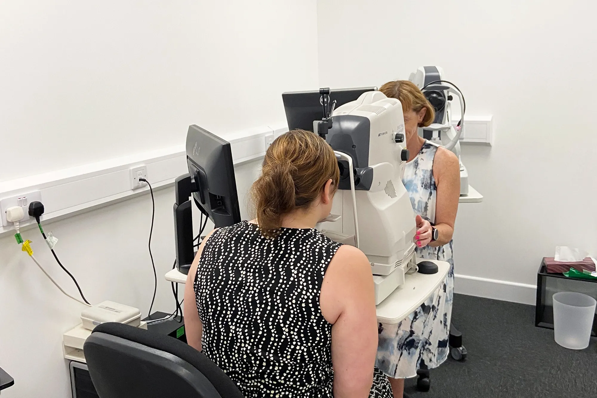 Woman undergoing an eye exam using a medical imaging device in a clinical setting.