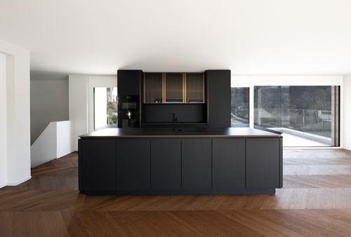 Narrow vertical window with dark glass set in a white textured wall with decorative molding at the base.