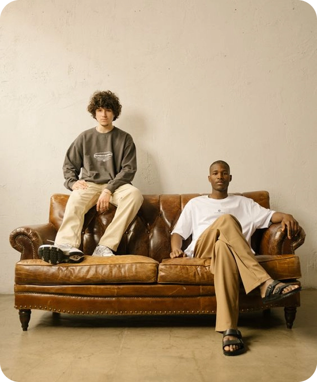 Two male clothing model sitting on a couch for a photoshoot 