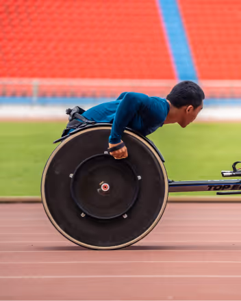 Athlete in a wheelchair racing on a track with a blurred stadium background.