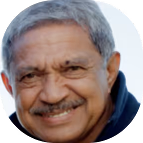 Close-up portrait of an elderly man with gray hair, a mustache, and a warm smile wearing a dark jacket.