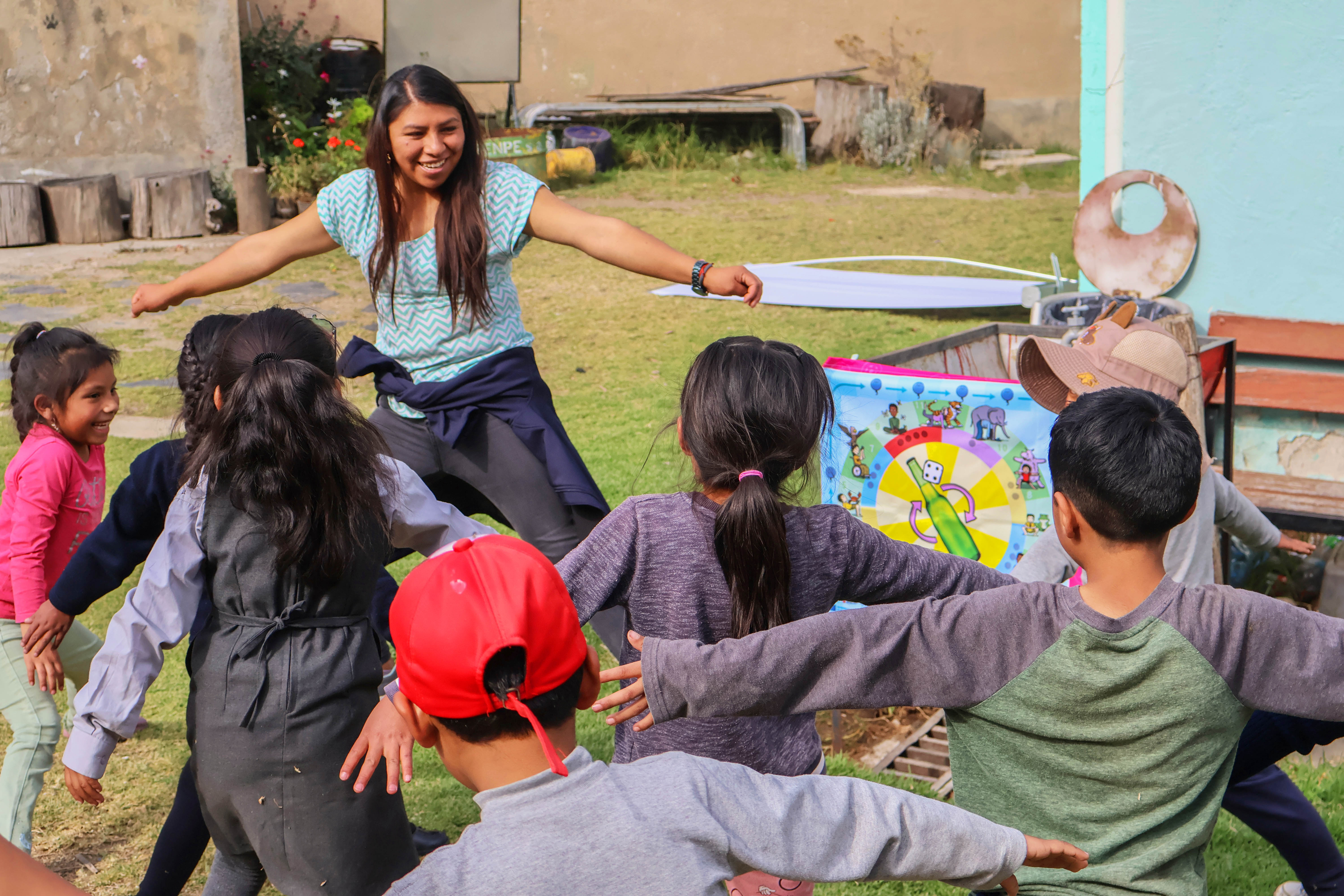 A woman leads a group of children in an outdoor FlagBag game