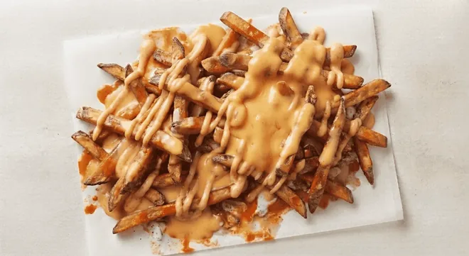 Wingstop Large Cheese Fries, fries covered in melted cheese sauce on white paper, nutrition and calories