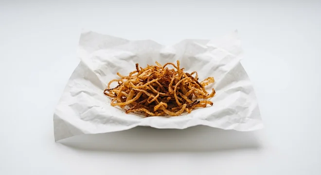 Chick-fil-A Crispy BBQ Onion Salad Topping, thin crispy fried onion strips with barbecue seasoning on white paper, nutrition and calories