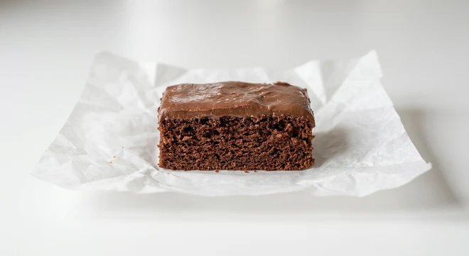 Greggs Chocolate Cake Bar, chocolate sponge slice with chocolate icing on white paper, nutrition and calories