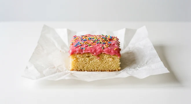 Greggs Tottenham Cake, sponge square with pink icing and sprinkles on white paper, nutrition and calories