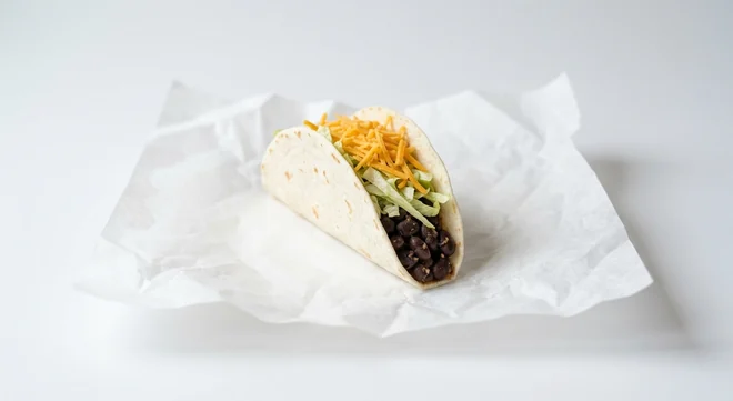 Taco Bell Soft Taco - Black Beans, soft flour taco with black beans, lettuce and cheddar on white paper, nutrition and calories