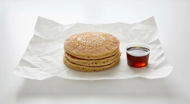Burger King US Pancake Platter, a stack of three fluffy pancakes with a pot of syrup on white paper, nutrition and calories