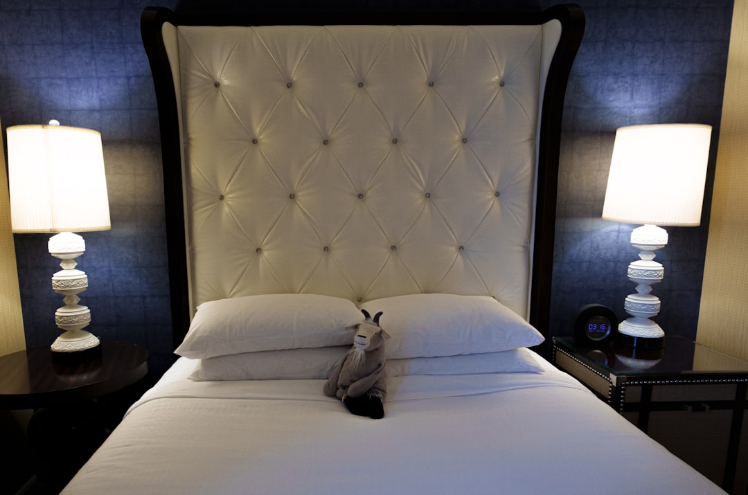 a bed with a white headboard and two lamps