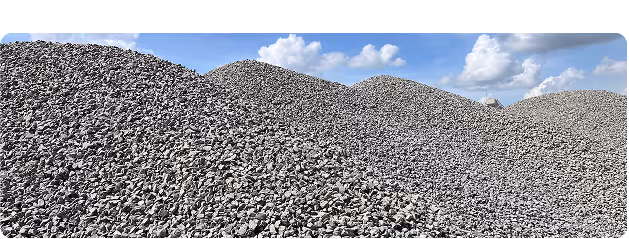 Large piles of crushed gray stones or gravel under a sky with clouds.