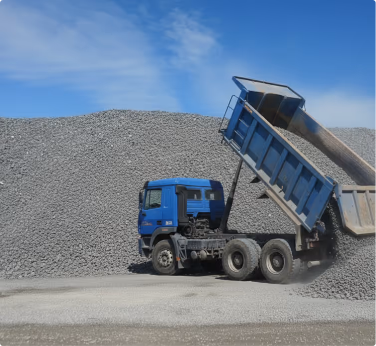 Blue dump truck unloading gravel onto a large pile under a clear blue sky.