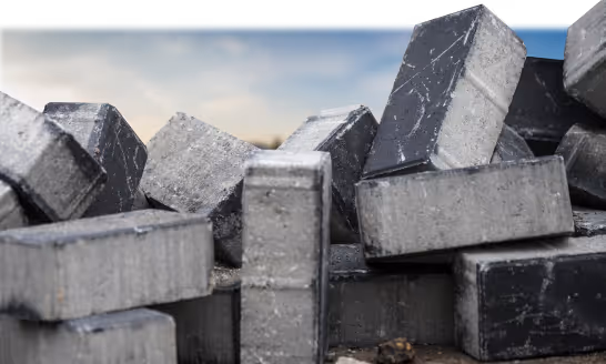 Stack of gray concrete bricks or blocks piled together outdoors under a cloudy sky.