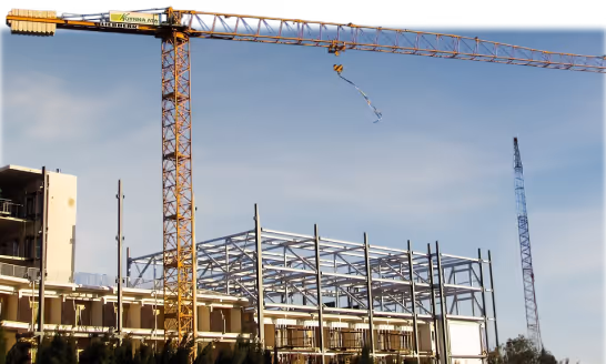 Construction site with a yellow crane and a partially built steel frame building under clear sky.