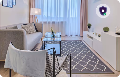 Modern living room with gray sofa, patterned rug, glass coffee tables, and sheer curtains over large window.