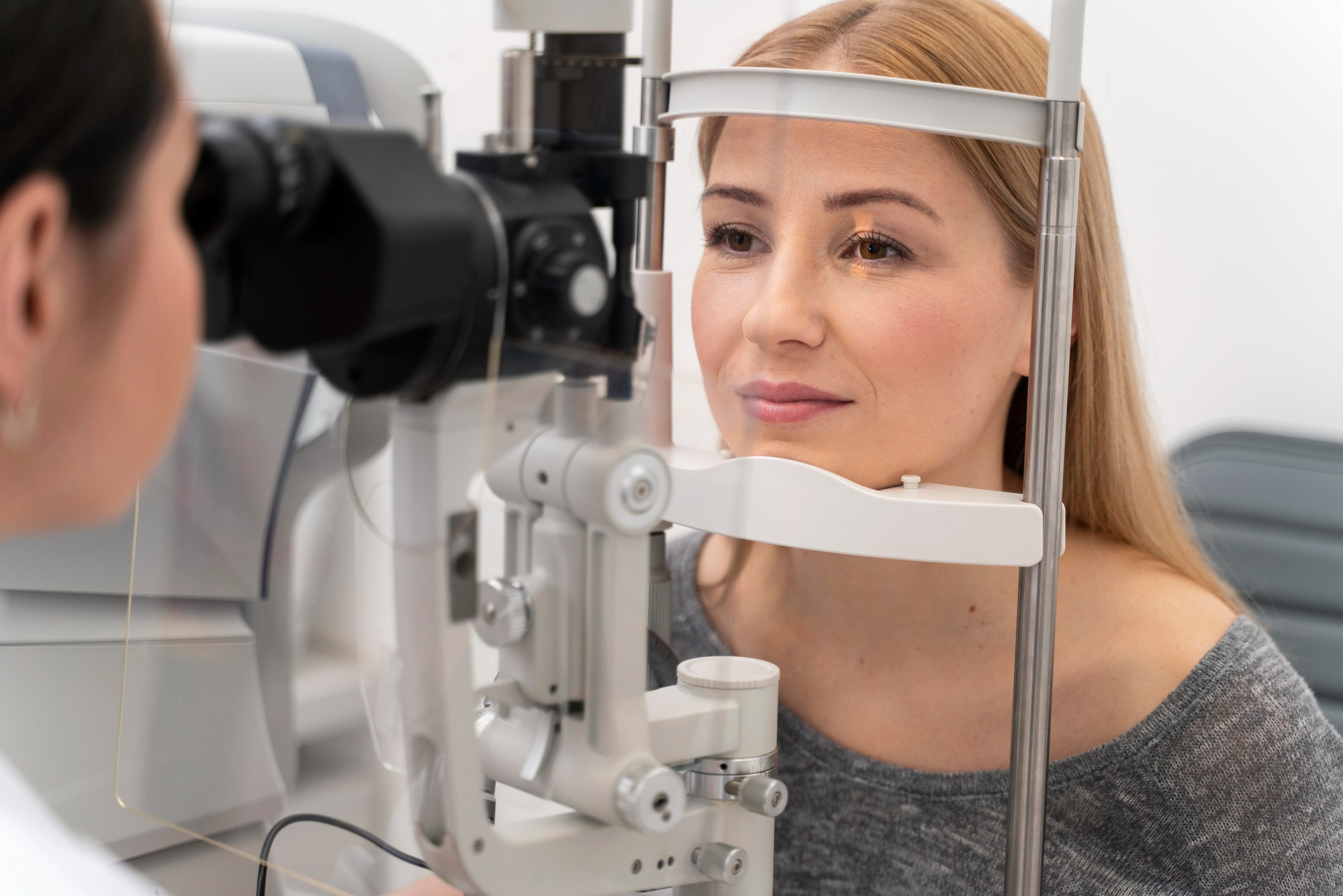 Woman undergoing an eye exam using a slit lamp at an optometrist's office.
