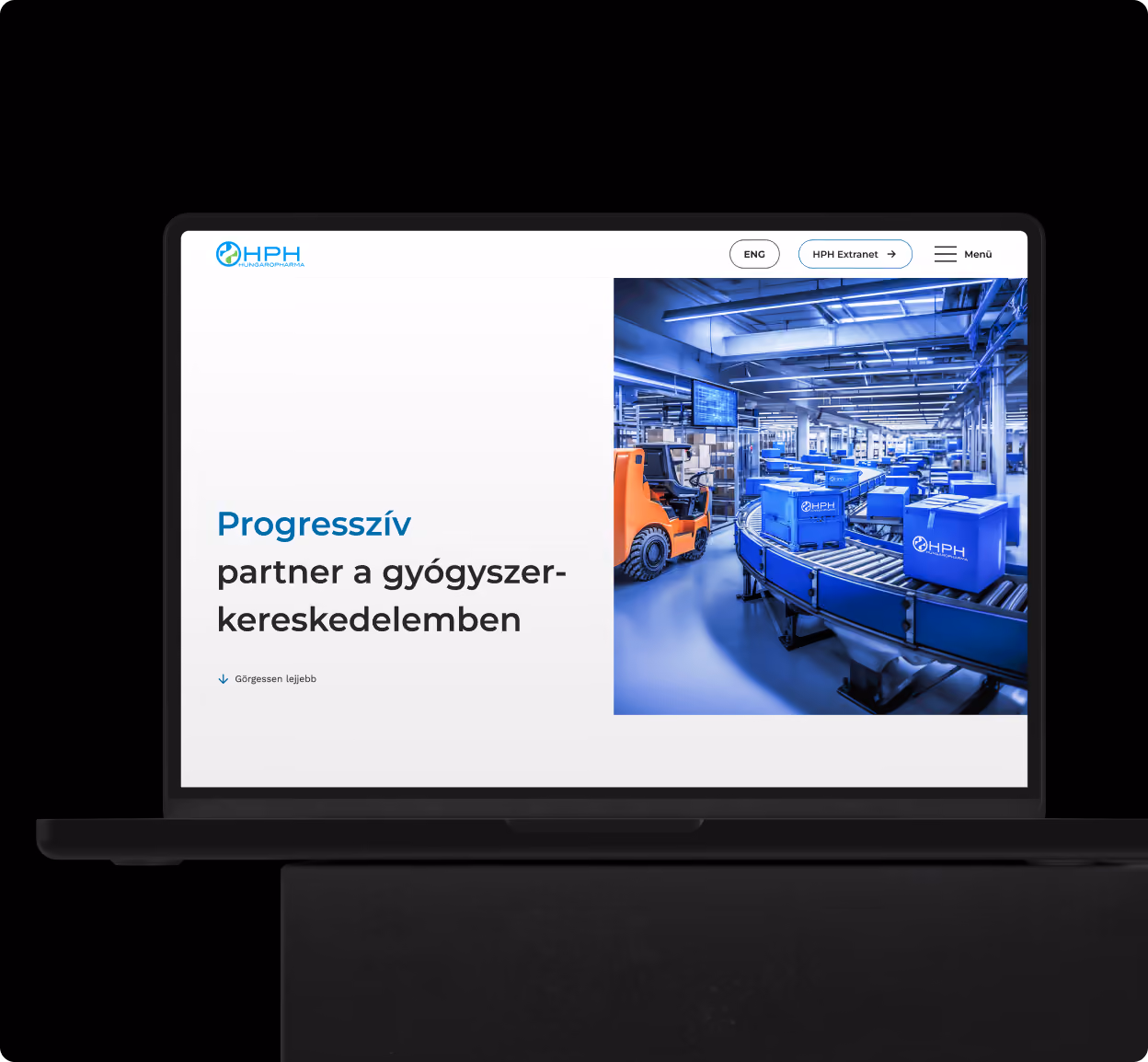 Laptop screen showing a website with a slogan in Hungarian: 'Progresszív partner a gyógyszer-kereskedelemben' next to an image of a blue-toned warehouse with conveyor belts carrying blue boxes labeled HPH and an orange forklift.