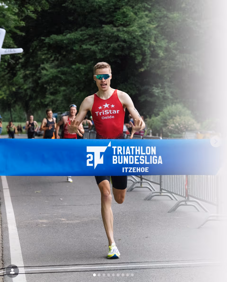 Triathlet Matthias G. überquert als Erster das Zielband der Triathlon Bundesliga in Itzehoe auf einer asphaltierten Straße.