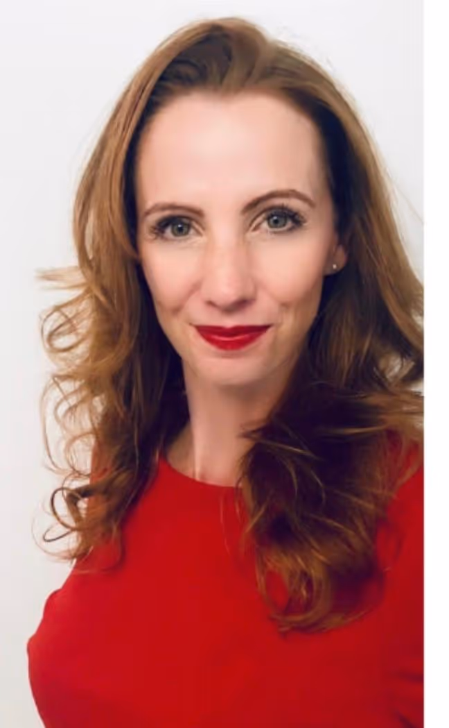 Rebecca Soetebier, die ein rotes Oberteil trägt und roten Lippenstift aufgetragen hat.