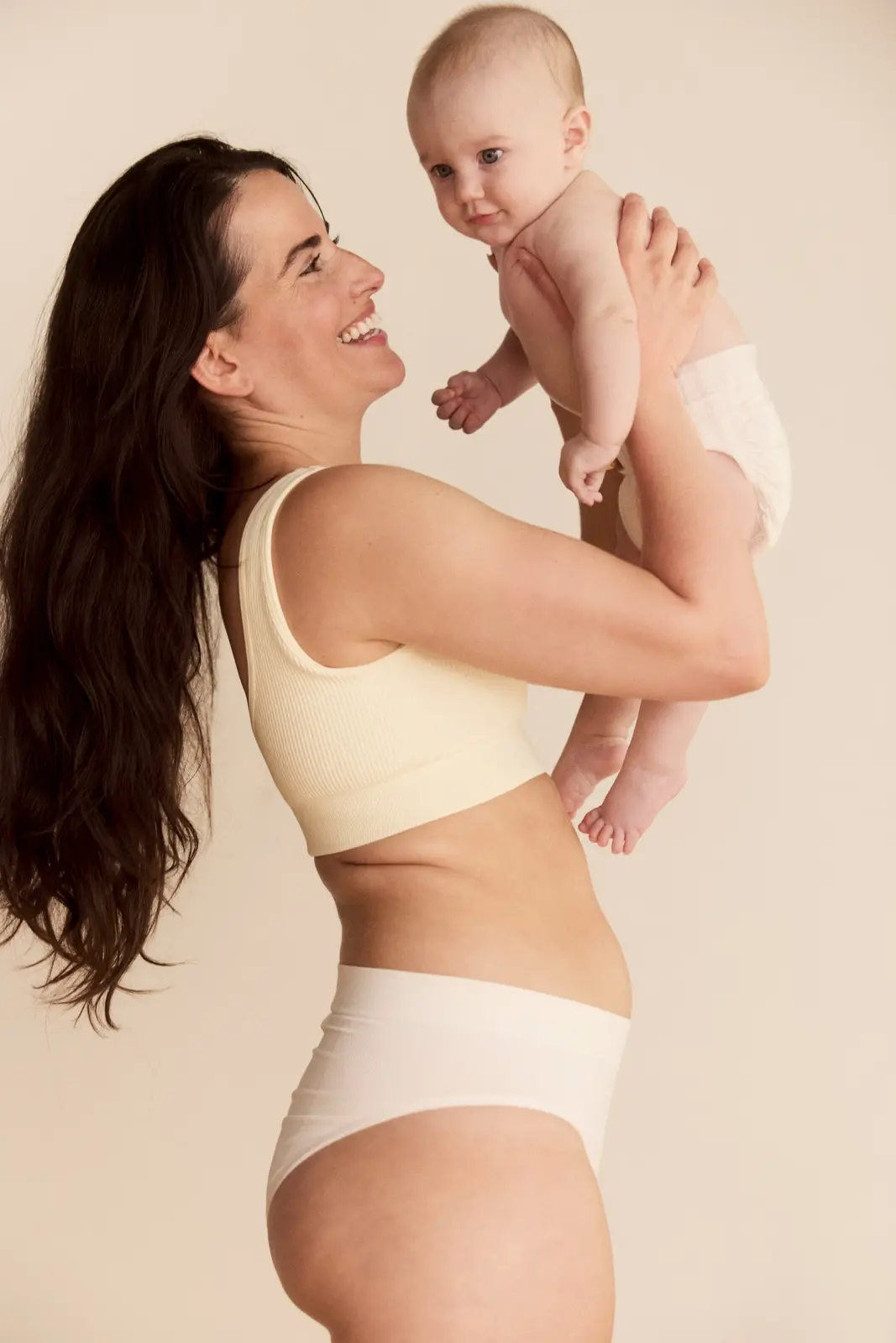Mother lifting her baby, feeling confident in her skin after Advanced Body Contouring