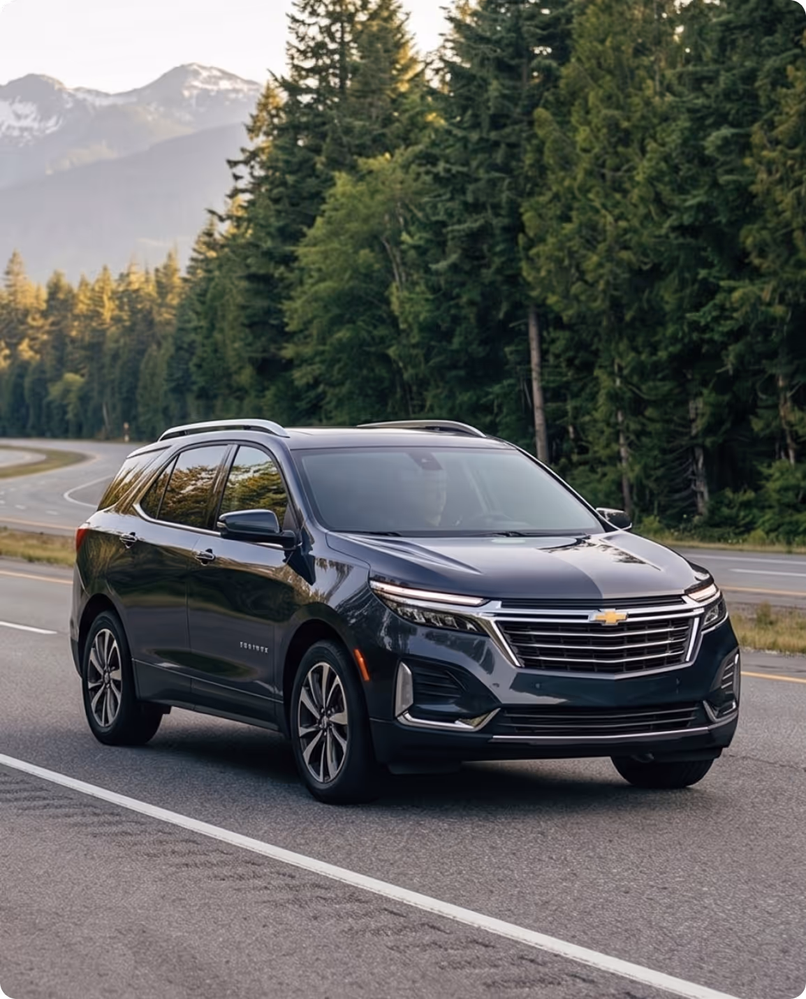 Black Chevrolet Traverse SUV driving on a road with forest and mountains in the background.