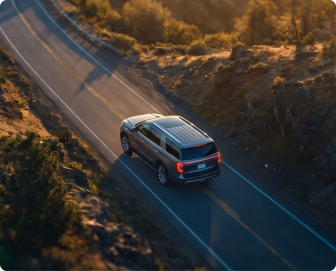 Silver SUV driving on a winding road next to a grassy hill with an overlay showing July mileage reimbursement details.