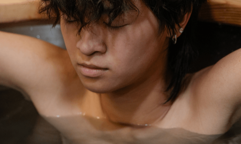 Guest fully immersed in a cold plunge, eyes closed in focus