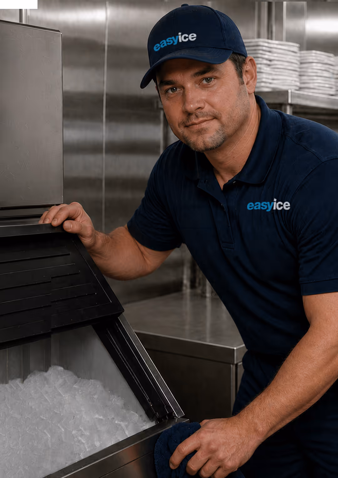 Man in easyice uniform opening ice machine filled with ice in a stainless steel kitchen.